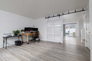 Office space with a barn door and light wood-type flooring