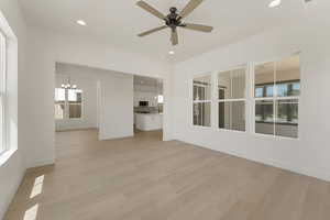 Unfurnished living room featuring recessed lighting, a chandelier, light wood-style flooring, and a ceiling fan