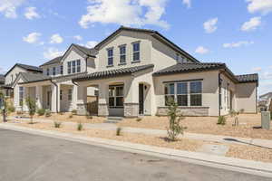 View of front of house featuring a porch, stone siding, stucco siding, and a tiled roof