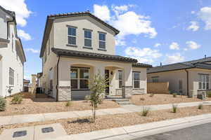 Mediterranean / spanish-style home with covered porch, stone siding, a tiled roof, and stucco siding