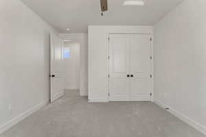 Unfurnished bedroom with light colored carpet, a closet, and a ceiling fan