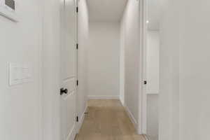 Corridor with light wood-style flooring and baseboards