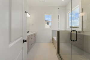 Bathroom featuring vanity, plenty of natural light, a stall shower, and light tile patterned floors