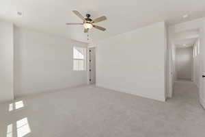 Empty room featuring light colored carpet and ceiling fan