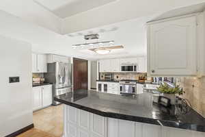 Huge Kitchen with a peninsula, white cabinets, and abundant counterspace