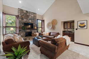 Living room featuring floor to ceiling stone fireplace, vaulted ceilings, wet bar and plantation shutters.