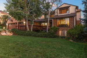 Back of house at dusk featuring brick siding, a yard, a garage, and stucco siding