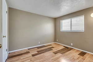 Spare room with a textured ceiling and light wood-type flooring
