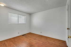 Empty room with wood finished floors and a textured ceiling