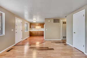 Kitchen with brown cabinetry, a textured ceiling, light countertops, and light wood-type flooring