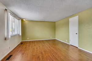 Empty room with light wood-type flooring and a textured ceiling
