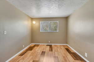 Spare room with light wood-style flooring and a textured ceiling