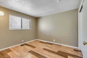 Unfurnished room with light wood-type flooring and a textured ceiling