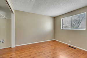 Unfurnished bedroom featuring a closet, light wood-style flooring, and a textured ceiling