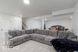 Living area with carpet floors, recessed lighting, and stairway
