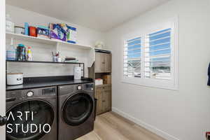 Laundry area featuring light wood-style flooring, washer and clothes dryer, and cabinet space