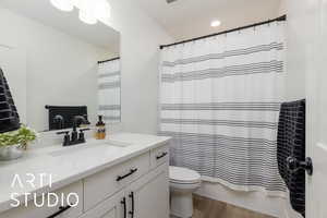 Full bathroom with vanity, light wood-style floors, shower / bath combo, and recessed lighting