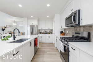 Kitchen with stainless steel appliances, recessed lighting, decorative light fixtures, white cabinetry, and light stone countertops