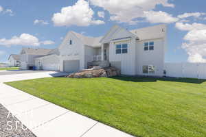 View of front of house featuring board and batten siding, concrete driveway, a front yard, an attached garage, and a residential view