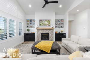 Living room with recessed lighting, a tiled fireplace, wood finished floors, ceiling fan, and vaulted ceiling