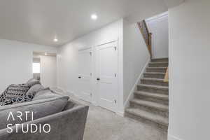 Living area with light colored carpet, stairway, and recessed lighting