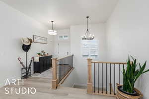Stairs featuring a chandelier and wood finished floors