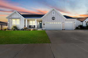 Modern inspired farmhouse with board and batten siding, an attached garage, covered porch, a standing seam roof, and a metal roof