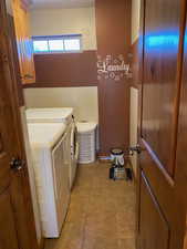 Laundry room with cabinet space, light tile patterned flooring, and washer and dryer
