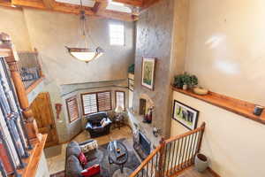 Living area featuring a stone fireplace, a high ceiling, beam ceiling, and tile patterned flooring