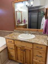 Bathroom featuring vanity, a bath, a shower stall, a chandelier, and tile patterned flooring