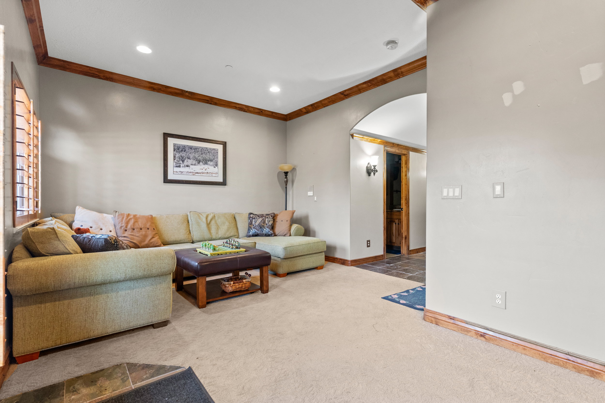 Carpeted living area with arched walkways, ornamental molding, and recessed lighting