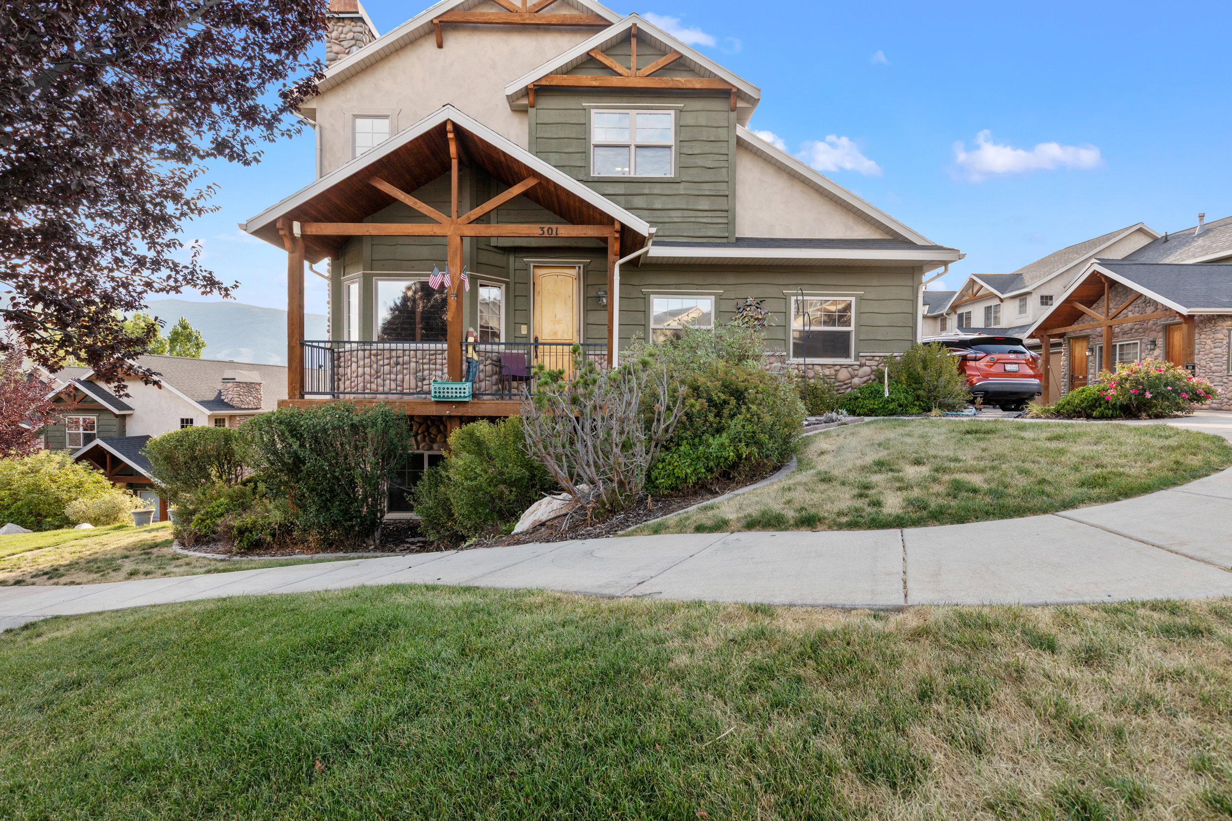 Craftsman house with a front yard, stone siding, a chimney, and covered porch