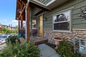 Property entrance with covered porch and stone siding