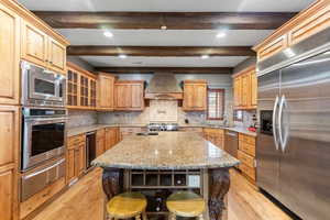 Kitchen with built in appliances, light wood-type flooring, tasteful backsplash, beamed ceiling, and a warming drawer