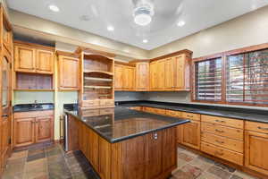 Kitchen featuring open shelves, a center island, recessed lighting, and dark stone finish floors
