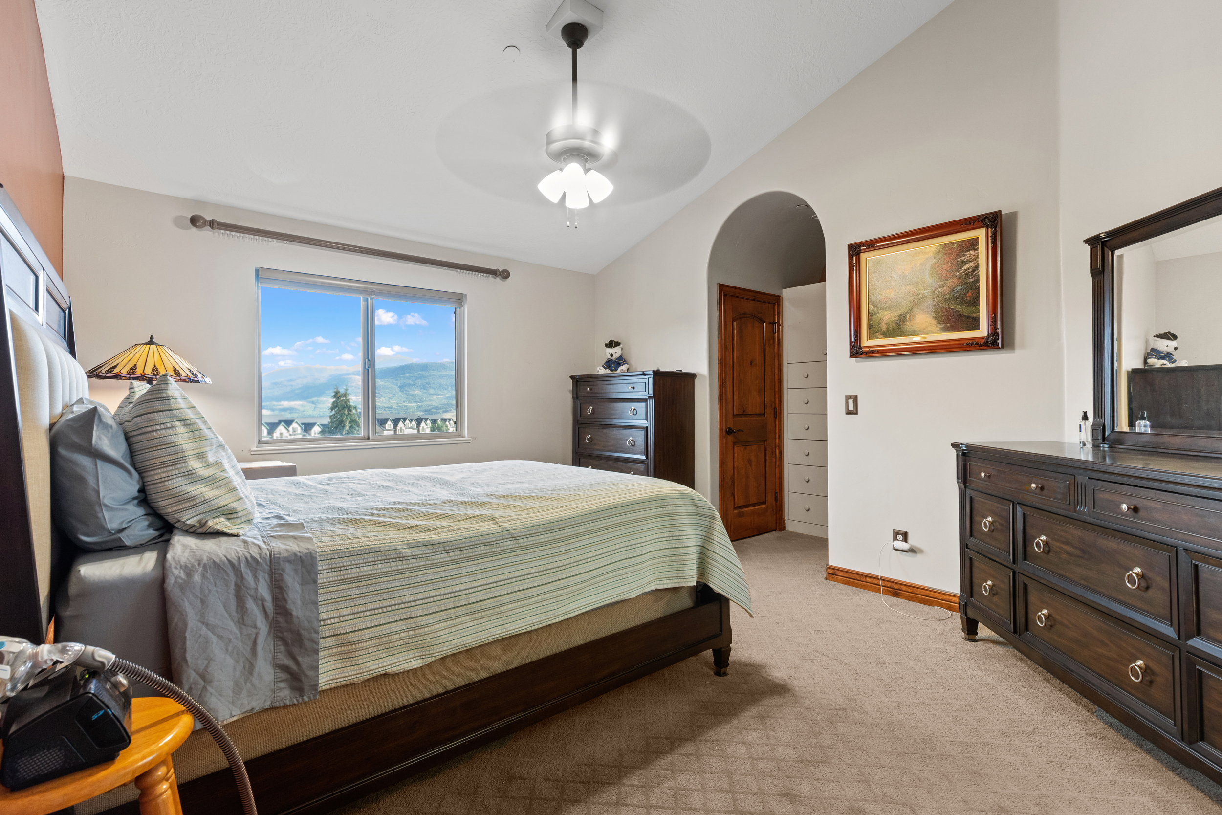 Bedroom featuring lofted ceiling, light carpet, arched walkways, and a ceiling fan