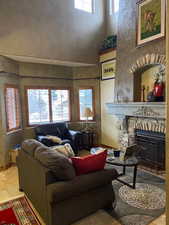 Tiled living area with a fireplace, a towering ceiling, and a textured wall