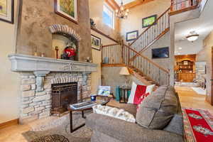Living room featuring a fireplace, a towering ceiling, a chandelier, and stairs