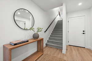 Stairs featuring carpet and entryway with wood finish LVP floors and recessed lighting