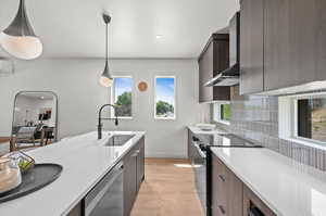 Kitchen with modern cabinets, black electric range, light quartz counters, decorative light fixtures, and light wood finished floors
