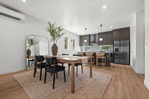 Dining area with light wood-style floors, an AC wall unit, and recessed lighting