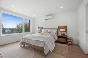 Primary Bedroom featuring room for a king-size bed light wood-style flooring, recessed lighting, and an AC wall unit