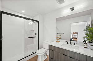 Full bath featuring vanity, a glass shower, recessed and decorative lighting, and light wood-style floors