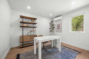 Office space featuring light wood finish LVP floors, recessed lighting, and a wall unit AC