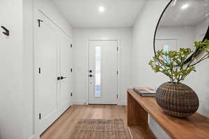 Entryway featuring light wood finish LVP flooring, coat closet, and recessed lighting