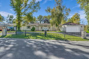 Ranch-style house featuring a fenced front yard, brick siding, a chimney, and driveway