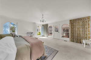 Carpeted bedroom featuring crown molding, multiple windows, and a chandelier