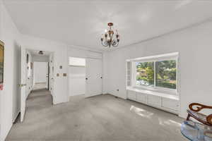 Unfurnished bedroom with light colored carpet, a chandelier, and a closet