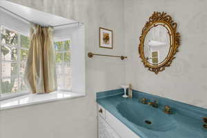 Bathroom featuring wallpapered walls and vanity
