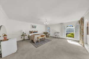 Bedroom with ornamental molding, carpet, and a chandelier